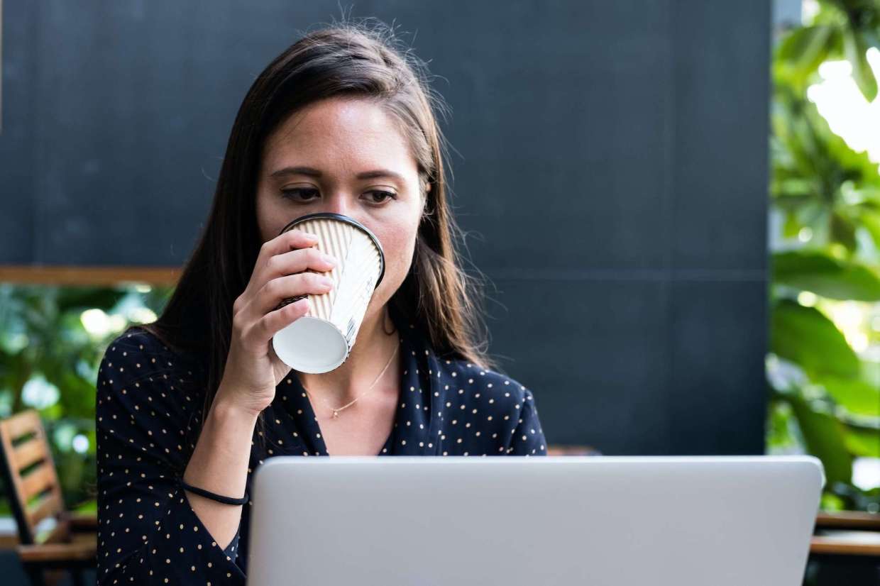 Woman Drinking Coffee while on Computer